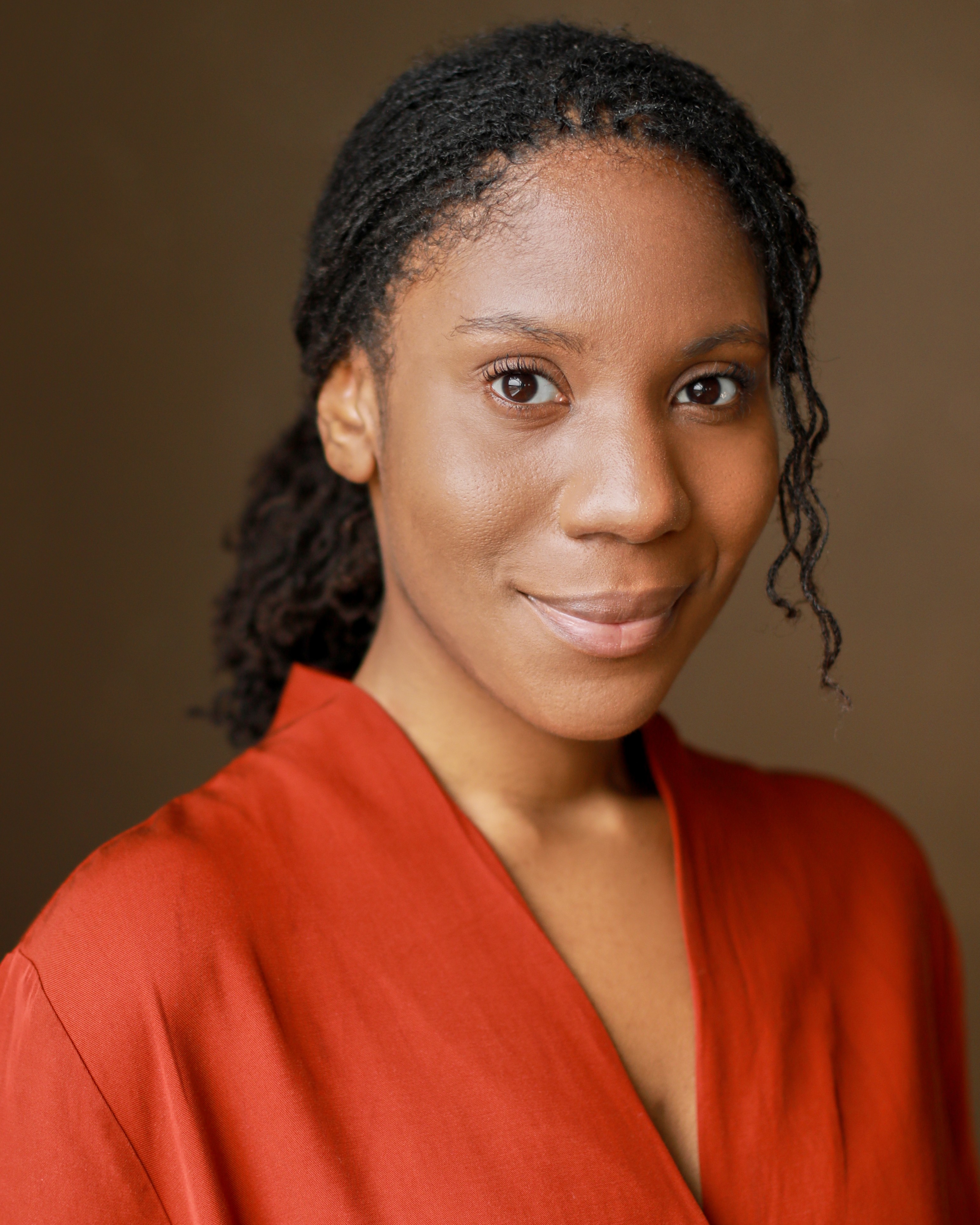 Portrait of a woman with brown hair on a flat gray background.